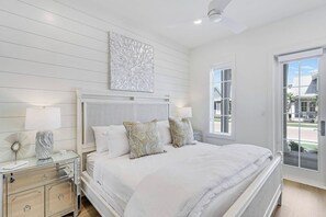 A bedroom with a bed, bedside lamps, a dresser, and a large window with a view. - Palmilla Beach Resort-226 Sunrise Avenue (Port Aransas)