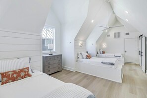 Ein modernes Schlafzimmer mit schrägem Dach, einem zentral platzierten Bett, einer Kommode und einem begehbaren Kleiderschrank.