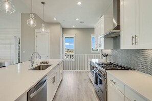 A modern kitchen with a central island, stainless steel appliances, and pendant lighting. - Palmilla Beach Resort-236 Sunset Avenue (Port Aransas)
