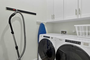 A laundry area with a front-loading washing machine, a hose, and a drying rack. - Palmilla Beach Resort-238 Sunset Avenue (Port Aransas)