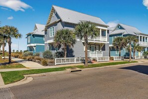 A two-story residential building with a grey roof and blue siding, featuring a front porch with a white railing. - Palmilla Beach Resort-238 Sunset Avenue (Port Aransas)