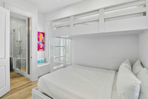A bedroom with a bunk bed, a glass shower enclosure, and a colorful abstract painting. - Palmilla Beach Resort-238 Sunset Avenue (Port Aransas)