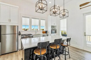 A modern kitchen with stainless steel appliances, a central island with bar stools, and pendant lighting. - Palmilla Beach Resort-241 Sunrise Avenue (Port Aransas)