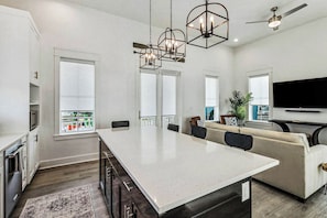 Een moderne keuken met een groot eiland, inbouwapparatuur en een zithoek met een bank en stoelen.