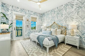 A bedroom with a bed, bedside tables, a window, and a door. - Palmilla Beach Resort-248 Sunrise Avenue (Port Aransas)