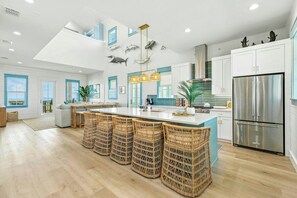 A modern kitchen with a central island, stainless steel appliances, and a view of the sea through large windows. - Palmilla Beach Resort-248 Sunrise Avenue (Port Aransas)