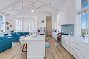 A spacious kitchen with white cabinetry, a central island, and a view to the outside. - Palmilla Beach Resort-250 Sunset Avenue (Port Aransas)