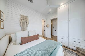 A bedroom with a bed, a macrame wall hanging, a wardrobe, and a door leading to another room. - Palmilla Beach Resort-260 Sunrise Avenue (Port Aransas)