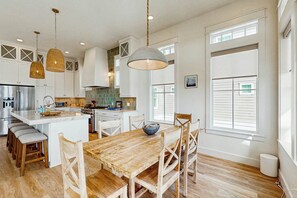Une cuisine spacieuse avec un grand îlot central, une table à manger en bois et des chaises.