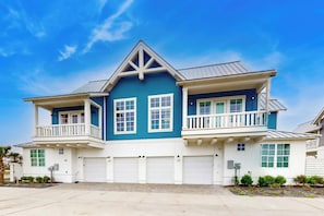 A two-story house with a gabled roof, multiple garage doors, and a front porch with railings. - Palmilla Beach Resort-288 Sunrise Avenue (Port Aransas)