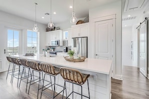 A modern kitchen with a large island, bar stools, and pendant lighting. - Palmilla Beach Resort-292 Sunrise Avenue (Port Aransas)