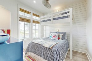 A bunk bed with patterned bedding, a desk with a bowl, and a window with blinds. - Palmilla Beach Resort-300 Mermaid Tail Lane (Port Aransas)