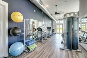 Ein Fitnessstudio mit Trainingsgeräten, einer Wand mit Fitnessmotiven und einem großen Fenster.