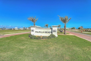 Schild für den Palmilla Beach, mit blauem Himmel und einem Parkplatz im Hintergrund.