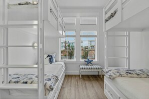 A room with bunk beds, a window with a view of houses, and a starfish decoration. - Palmilla Beach Resort-408 Mermaid Tail Lane (Port Aransas)