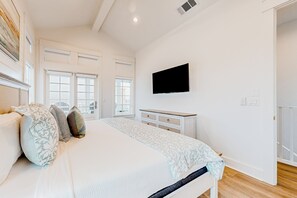 A bedroom with a bed, a dresser, a television mounted on the wall, and a window with a view of the outside. - Palmilla Beach Resort-416 Mermaid Tail Lane (Port Aransas)