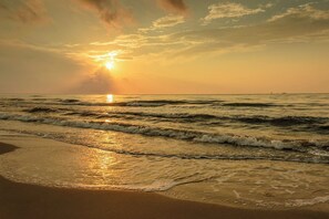 Une plage avec des vagues et un coucher de soleil.