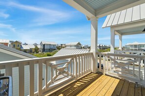 A wooden deck with a white railing, overlooking a row of houses with a clear sky above. - Palmilla Beach Resort-604 Sunset Avenue (Port Aransas)