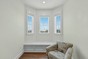 A room with a built-in bench, three windows, and a patterned armchair. - Palmilla Beach Resort-606 Sunset Avenue (Port Aransas)
