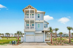 A multi-story residential building with a garage, balconies, and a landscaped front yard. - Palmilla Beach Resort-627 Sunset Avenue (Port Aransas)