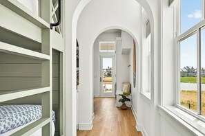 A narrow hallway with a wooden floor, white walls, and a large window on the right. - Palmilla Beach Resort-920 Sunset Avenue (Port Aransas)