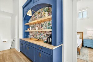 Una cocina con armarios azules, una encimera de madera y un salpicadero con motivos florales de colores.
