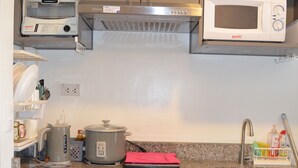 Cozinha com armários cinza, exaustor de aço inoxidável, micro-ondas branco, chaleira e pia.