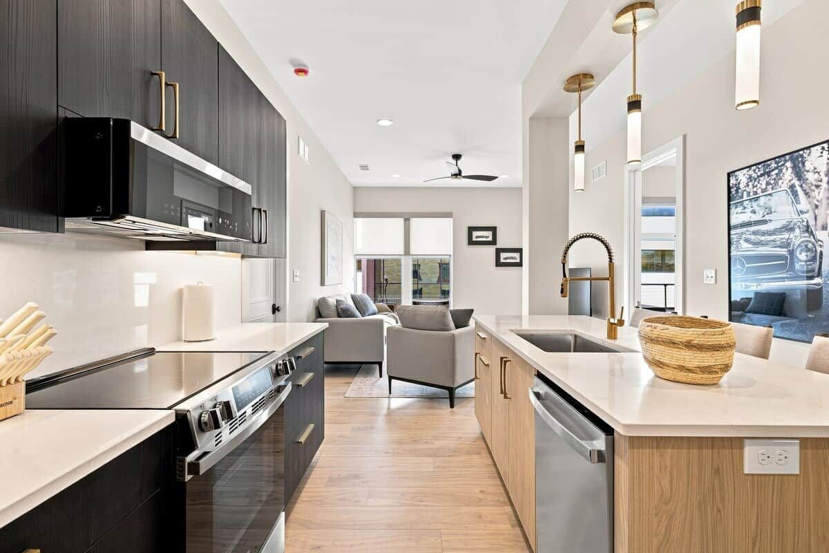 A modern kitchen with dark cabinetry, stainless steel appliances, and a light-colored countertop.