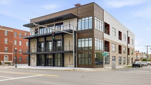 A modern building with a flat roof, large windows, and a visible street corner. - The Oaks · 2 Bedroom · 2 Bath · 1400SF (Owensboro)
