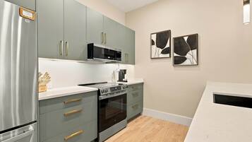 Una cocina moderna con electrodomésticos de acero inoxidable, armarios grises y encimera de madera.