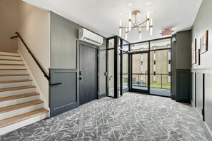 A hotel lobby with a staircase, a door, and a patterned carpet.