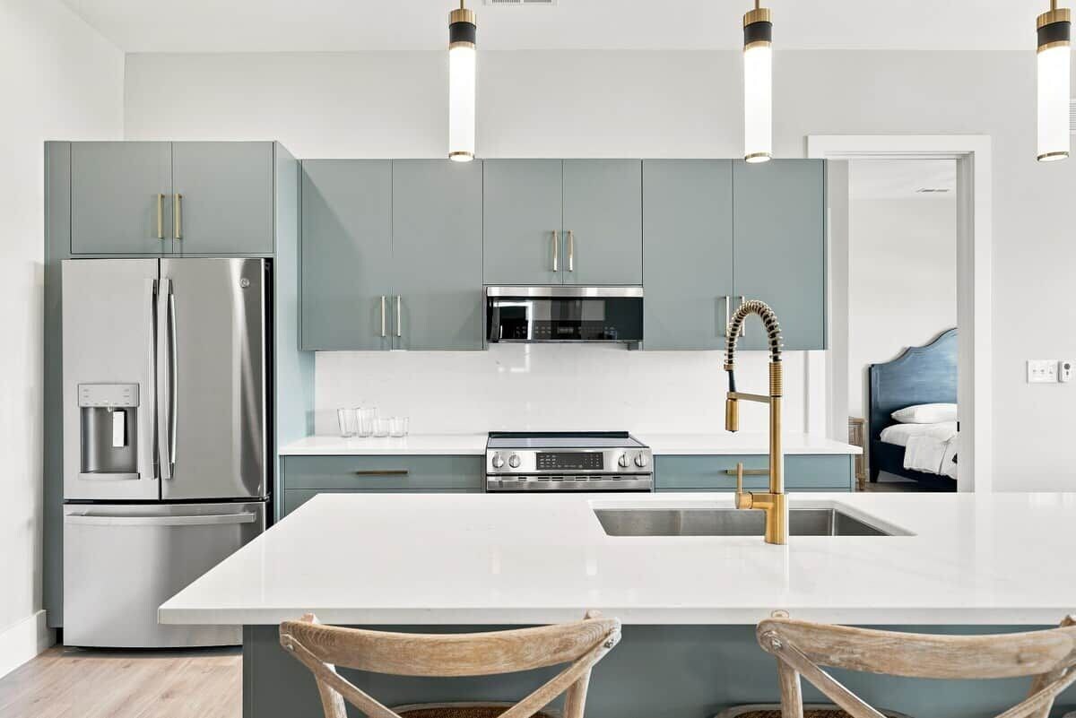 Una cocina moderna con una isla central, electrodomésticos de acero inoxidable y un horno empotrado.