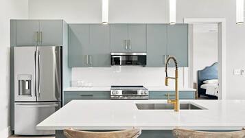 Una cocina moderna con una isla central, electrodomésticos de acero inoxidable y un horno empotrado.
