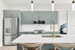 Una cocina moderna con una isla central, electrodomésticos de acero inoxidable y un horno empotrado.