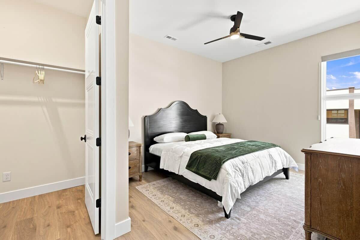 A bedroom with a bed, nightstand, lamp, and a ceiling fan.