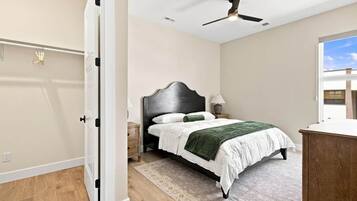 A bedroom with a bed, nightstand, lamp, and a ceiling fan.