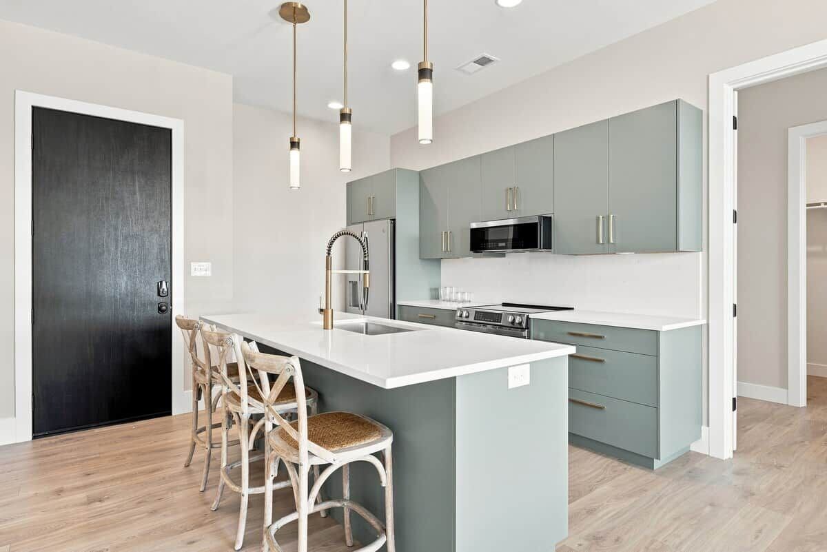 A modern kitchen with a central island, stainless steel appliances, and light-colored cabinetry.