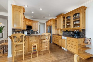 A kitchen with wooden cabinets, a granite countertop, a stainless steel refrigerator, and a coffee maker. - Laney’s Lake Retreat (Northport)