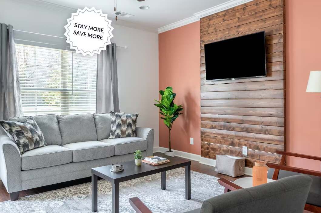 A living room with a sofa, coffee table, and a TV mounted on a wooden wall.