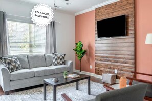 A living room with a sofa, coffee table, and a TV mounted on a wooden wall.