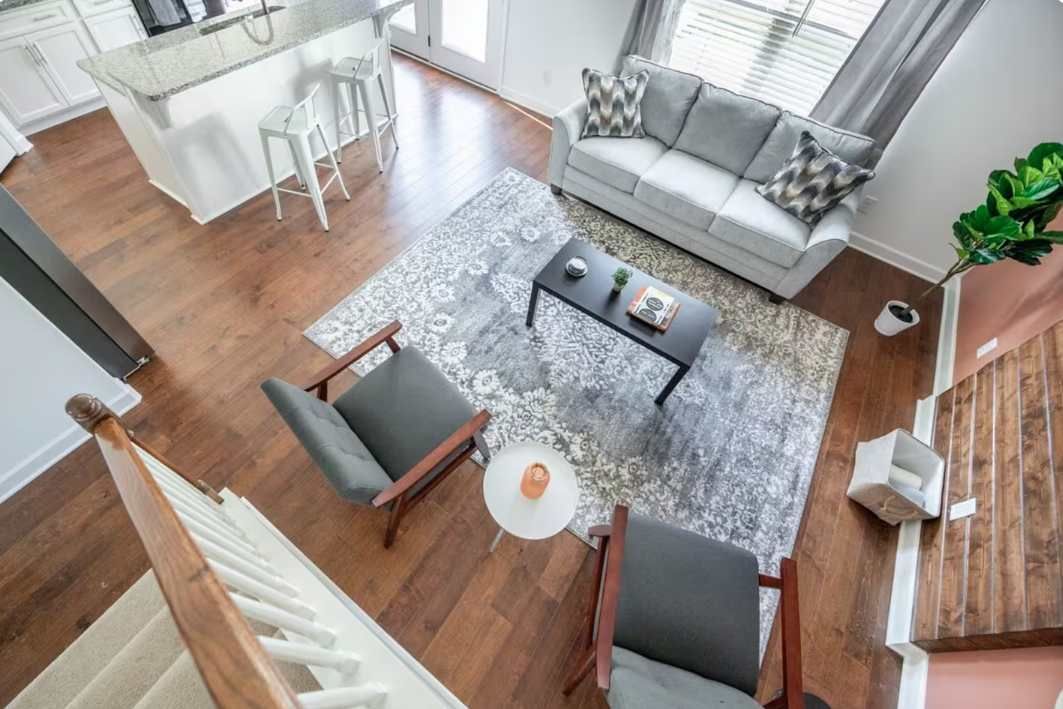 Una sala moderna con un sofá gris, una mesa de centro y una alfombra estampada.