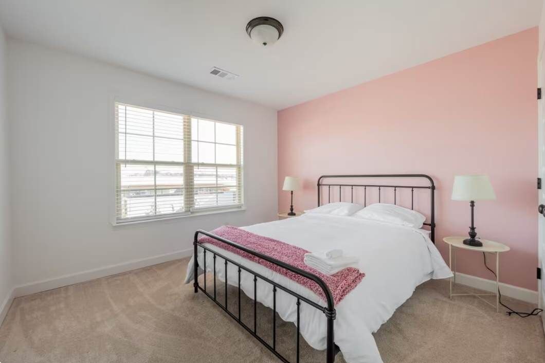 Una camera da letto con un letto singolo, due abat-jour, una finestra e una parete rosa.