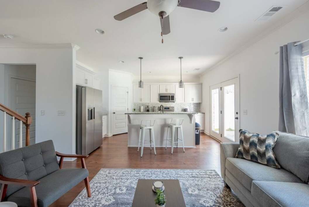 A modern living room with a sofa, a coffee table, and a dining area with a kitchen in the background.