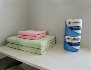 A stack of bath tissues on a white shelf.