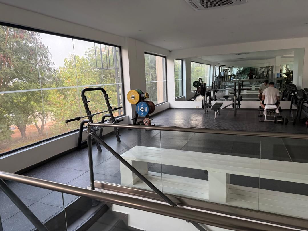 Ett gym med träningsutrustning, stora fönster och en trappa.
