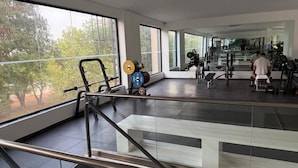 Un gimnasio con equipo de ejercicio, ventanas amplias y una escalera.
