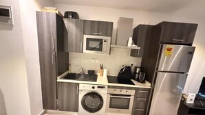 Cocina compacta con lavadora integrada, microondas, estufa y refrigerador.