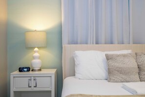 A neatly made bed with white bedding and two pillows, a bedside lamp on a nightstand, and a wall clock. - Near Disney 4BR Mario & Mickey Storey Lake Resort (Kissimmee)