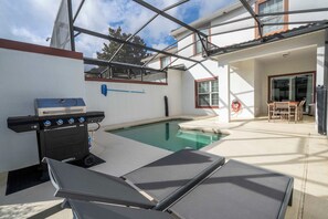 An outdoor pool area with a grill and lounge chairs. - Near Disney 4BR Mario & Mickey Storey Lake Resort (Kissimmee)