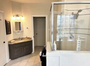 Une salle de bain avec une douche à parois de verre, un lavabo avec un meuble-vasque et un miroir.